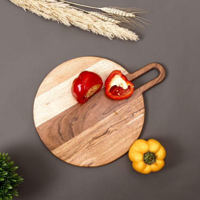Round mango wood serving board with red and yellow bell peppers, shot top-down for a home decor brand