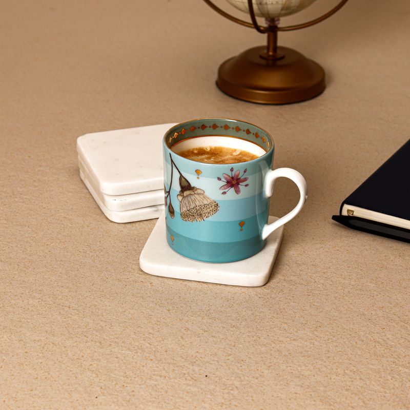 Hand-painted teal ceramic coffee mug on a marble coaster in a warm lifestyle flat-lay